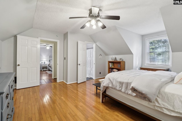 bedroom featuring a textured ceiling, ceiling fan, lofted ceiling, and light hardwood / wood-style flooring