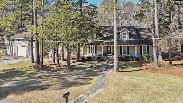 cape cod-style house featuring a front lawn, covered porch, and a garage