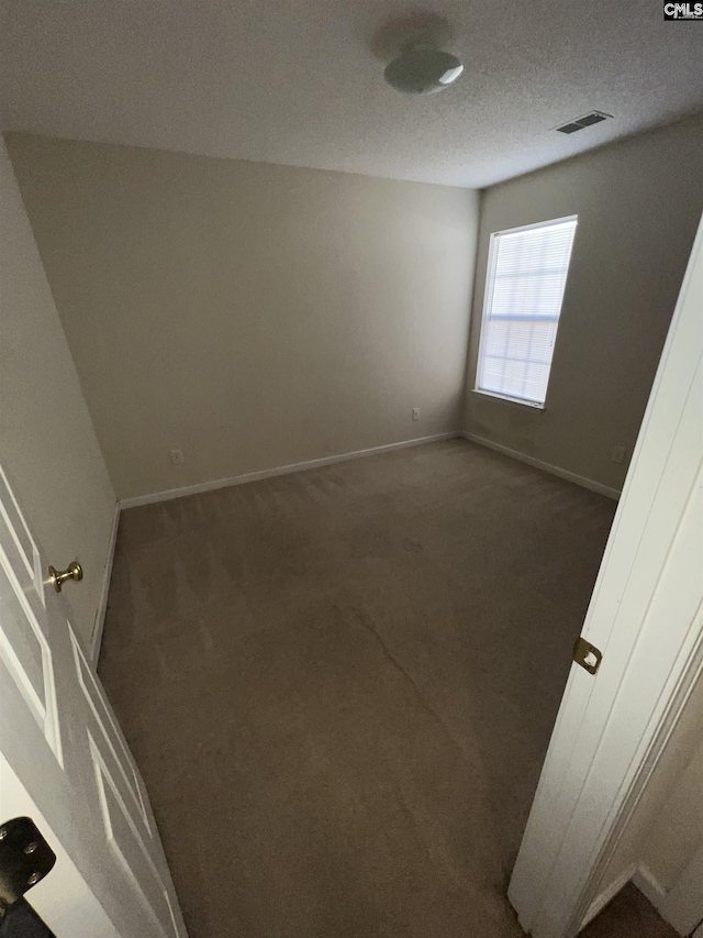 unfurnished bedroom featuring visible vents, carpet floors, a textured ceiling, and baseboards