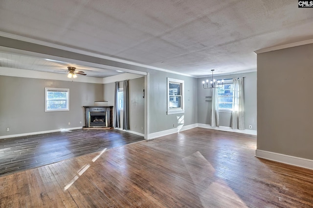 unfurnished living room with a healthy amount of sunlight, dark wood-type flooring, ceiling fan with notable chandelier, and ornamental molding