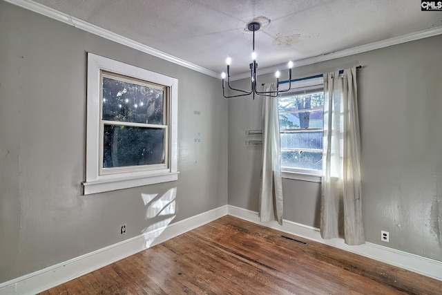 unfurnished dining area with wood-type flooring, a textured ceiling, a chandelier, and ornamental molding