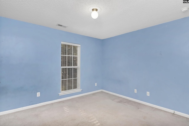 empty room with carpet floors and a textured ceiling