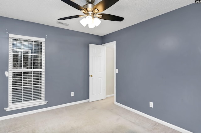 unfurnished room featuring ceiling fan, a textured ceiling, and light carpet