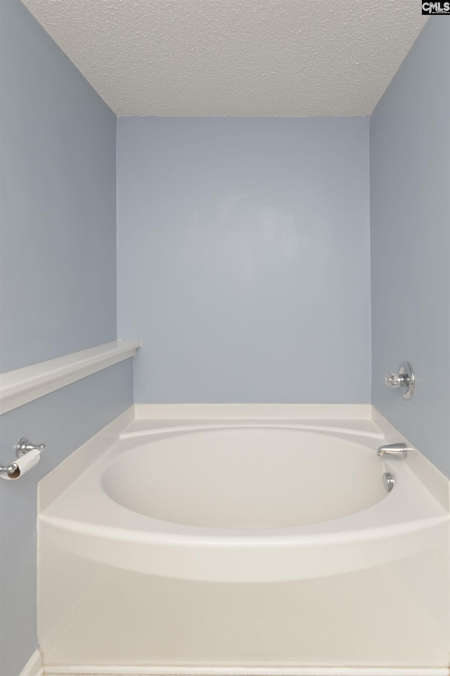 bathroom with a washtub and a textured ceiling