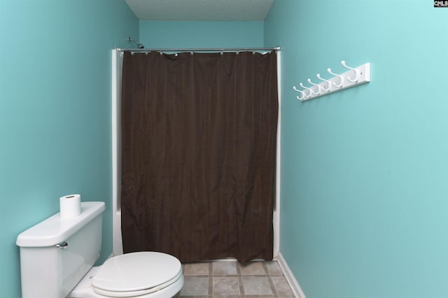 bathroom featuring a textured ceiling, toilet, and a shower with curtain