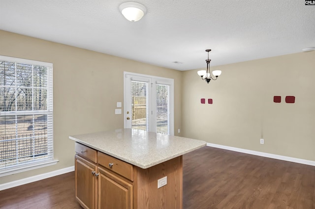 kitchen with dark wood-type flooring, an inviting chandelier, hanging light fixtures, and a center island