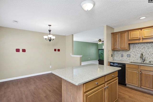 kitchen featuring tasteful backsplash, decorative light fixtures, dishwasher, light stone countertops, and a center island