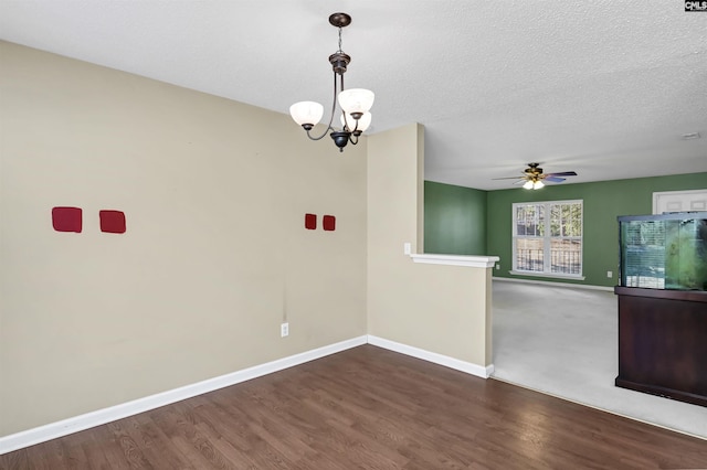 unfurnished room with a textured ceiling, ceiling fan with notable chandelier, and dark hardwood / wood-style floors