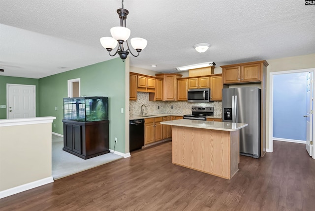 kitchen with stainless steel appliances, a kitchen island, hanging light fixtures, a chandelier, and sink