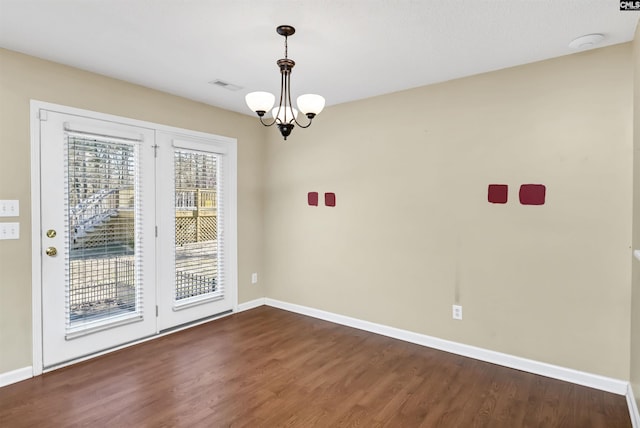 unfurnished dining area featuring a chandelier and dark hardwood / wood-style floors