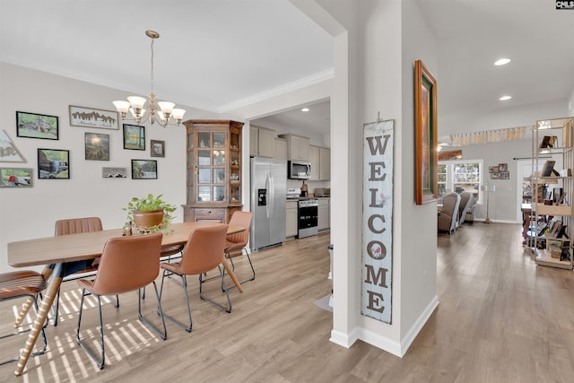 dining room with light hardwood / wood-style floors, ornamental molding, and a chandelier