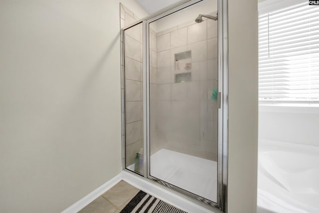 bathroom with a shower with shower door, plenty of natural light, and tile patterned floors