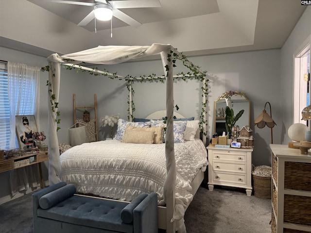 bedroom featuring ceiling fan, a tray ceiling, and carpet floors