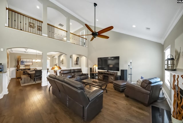 living room with dark wood-type flooring, a fireplace, high vaulted ceiling, crown molding, and ceiling fan with notable chandelier