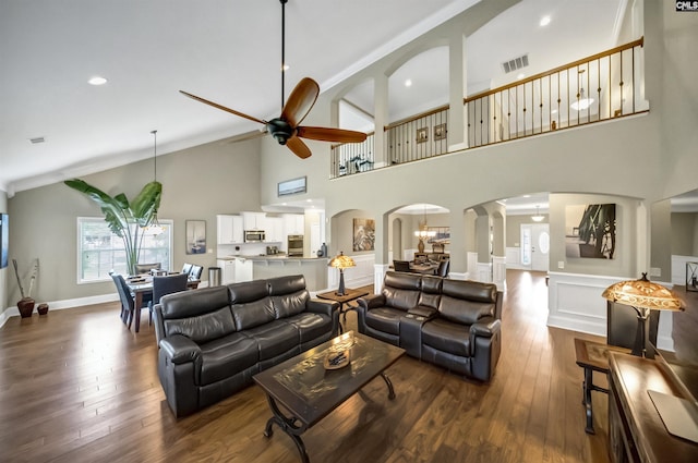 living room with ceiling fan with notable chandelier, a high ceiling, and hardwood / wood-style flooring