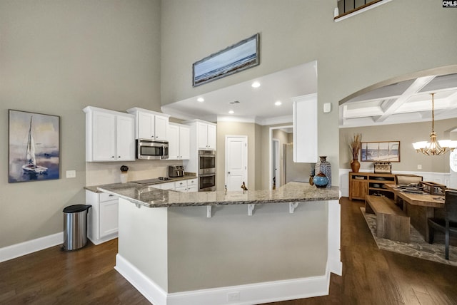 kitchen featuring appliances with stainless steel finishes, white cabinetry, kitchen peninsula, beam ceiling, and coffered ceiling