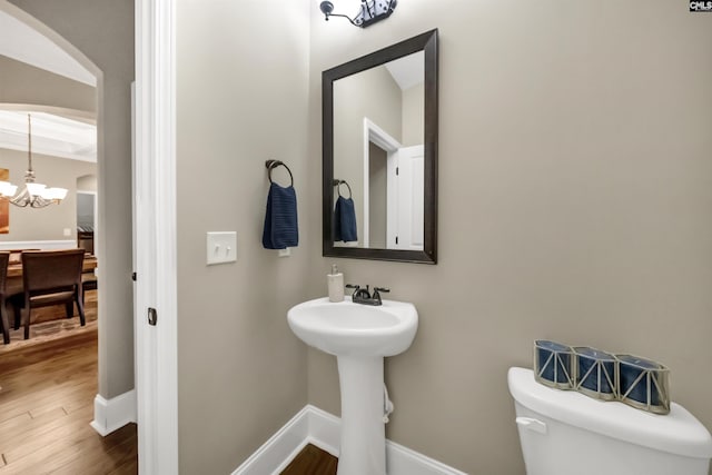 bathroom with toilet, a chandelier, and hardwood / wood-style floors