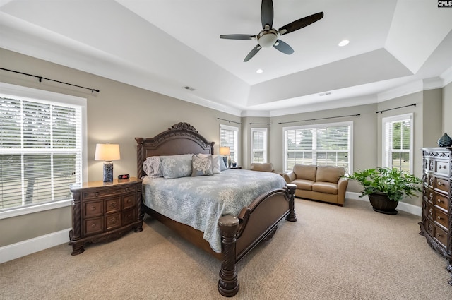 bedroom with ceiling fan, light colored carpet, and a raised ceiling