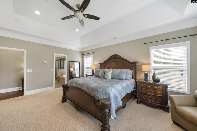 carpeted bedroom with ceiling fan, a tray ceiling, and connected bathroom