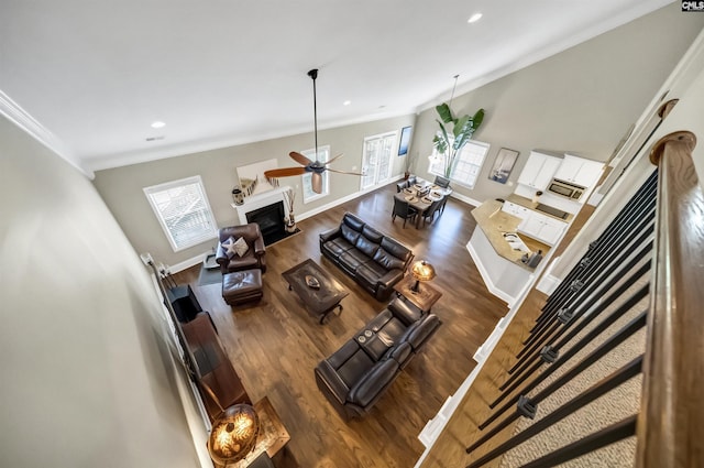 living room featuring ceiling fan, wood-type flooring, and ornamental molding