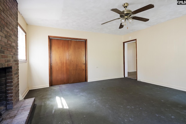 unfurnished bedroom with ceiling fan, a closet, and a brick fireplace