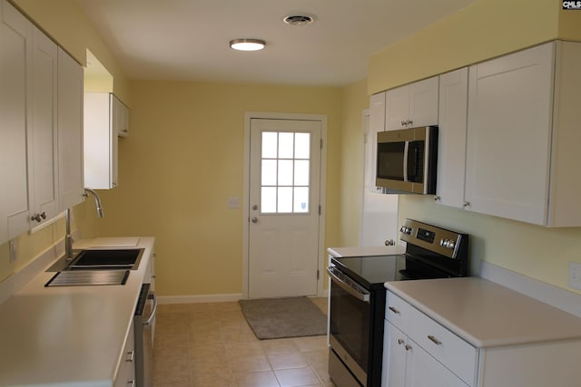 kitchen with light tile patterned floors, sink, white cabinets, and stainless steel appliances