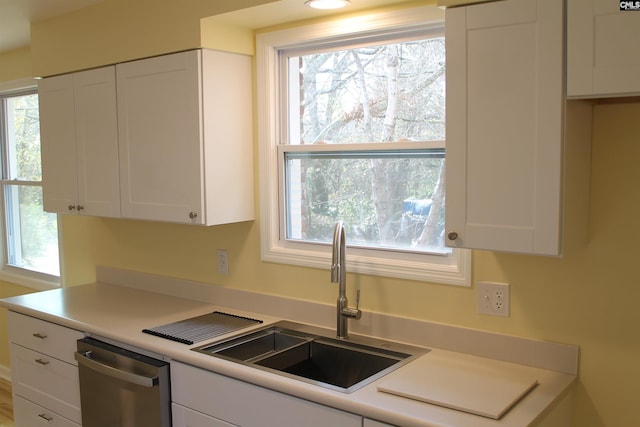 kitchen featuring stainless steel dishwasher, white cabinets, and sink