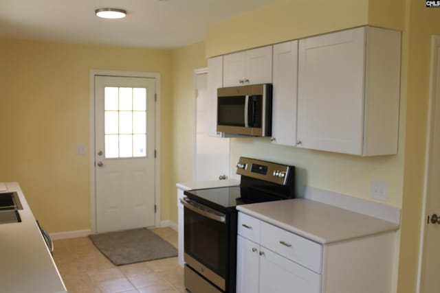 kitchen featuring light tile patterned flooring, stainless steel appliances, and white cabinetry