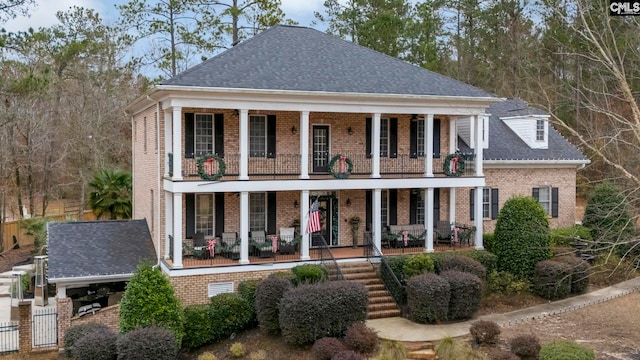 neoclassical home featuring covered porch and a balcony