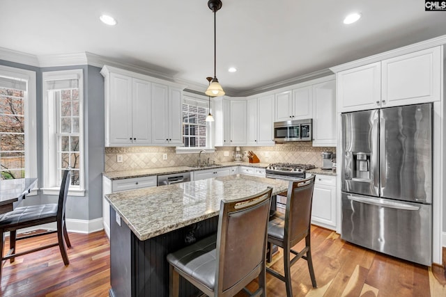 kitchen with white cabinetry, stainless steel appliances, light wood-type flooring, hanging light fixtures, and sink