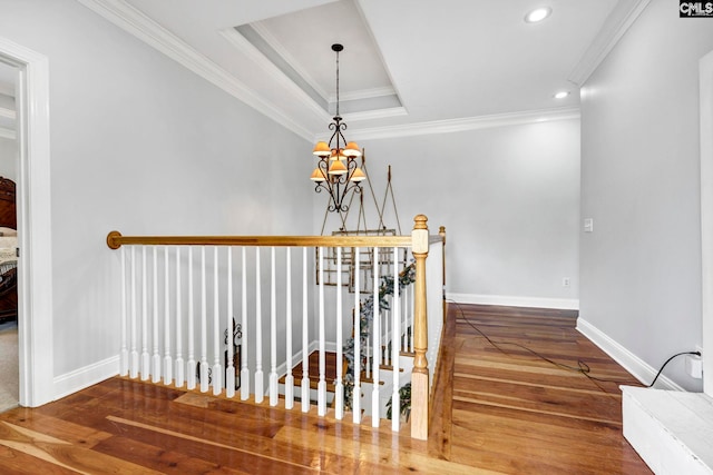 stairway with a chandelier, ornamental molding, hardwood / wood-style floors, and a tray ceiling