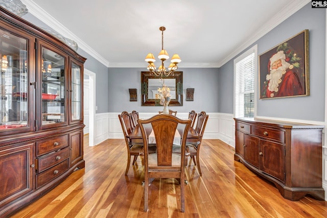 dining space featuring a chandelier, ornamental molding, and light hardwood / wood-style flooring