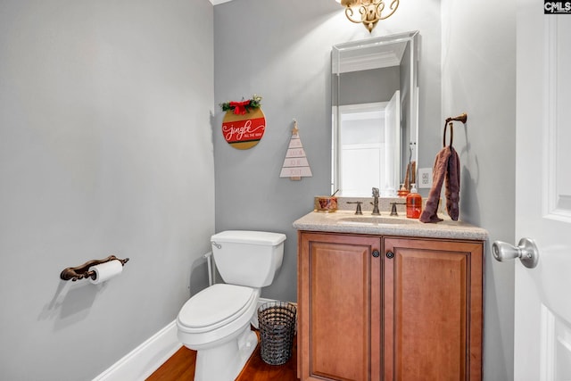 bathroom with toilet, ornamental molding, hardwood / wood-style flooring, and vanity