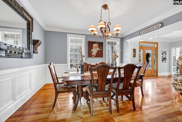 dining room with a wealth of natural light, crown molding, a chandelier, and light hardwood / wood-style flooring