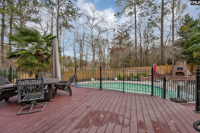 deck with an outdoor brick fireplace and a covered pool