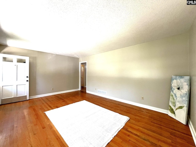 empty room with wood-type flooring and a textured ceiling