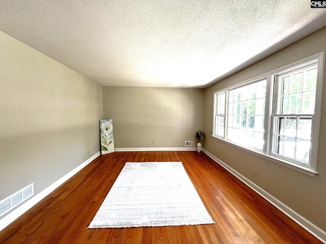 empty room with a textured ceiling and hardwood / wood-style flooring