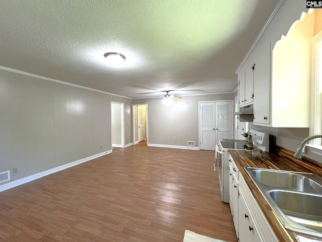 kitchen with a textured ceiling, white cabinets, white electric range, wooden counters, and sink