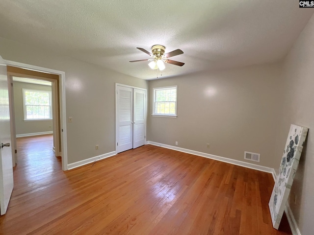 unfurnished bedroom featuring a textured ceiling, ceiling fan, a closet, and light hardwood / wood-style flooring