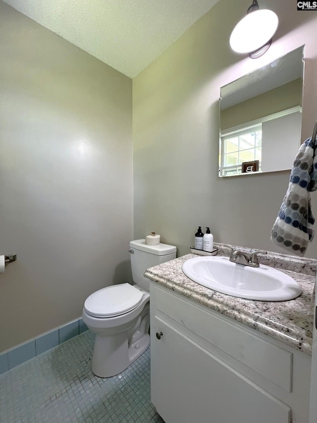 bathroom featuring a textured ceiling, toilet, vanity, and tile patterned flooring