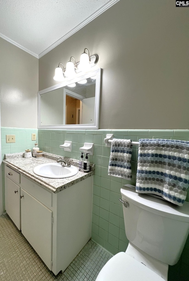 bathroom featuring toilet, tile walls, a textured ceiling, crown molding, and vanity