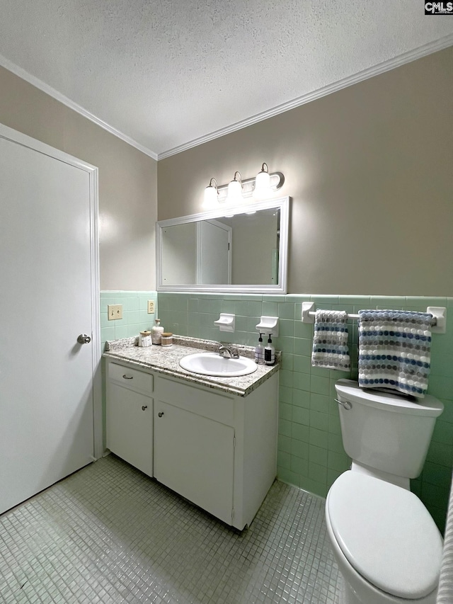 bathroom featuring toilet, vanity, tile walls, ornamental molding, and a textured ceiling