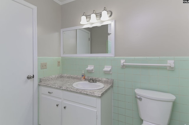 bathroom with tile walls, toilet, vanity, and crown molding