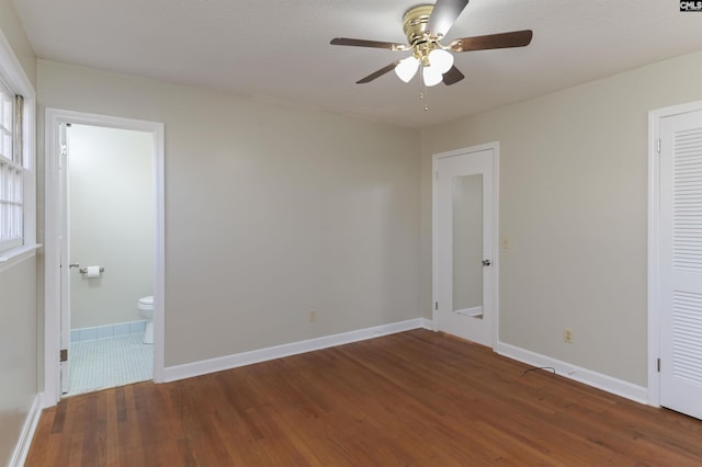 unfurnished bedroom featuring dark wood-type flooring, ceiling fan, and ensuite bathroom