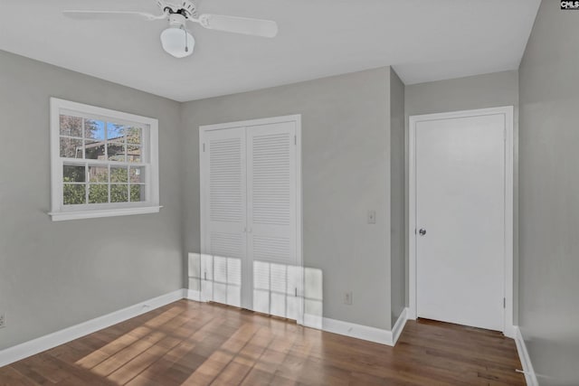 unfurnished bedroom featuring ceiling fan, a closet, and dark wood-type flooring