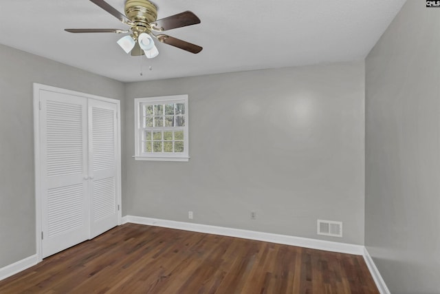 unfurnished bedroom featuring ceiling fan, a closet, and dark wood-type flooring