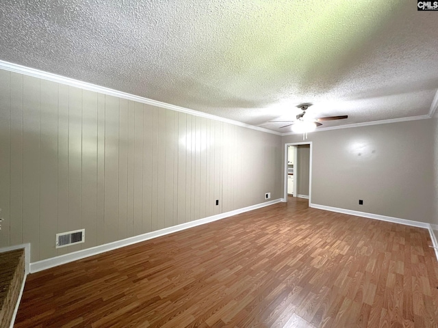 unfurnished room with ceiling fan, wooden walls, crown molding, and hardwood / wood-style floors