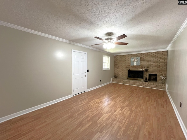 unfurnished living room featuring a textured ceiling, hardwood / wood-style floors, ceiling fan, a brick fireplace, and crown molding