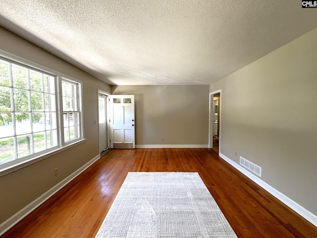 spare room featuring a textured ceiling and dark wood-type flooring