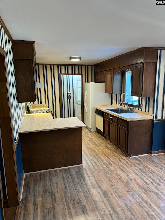 kitchen featuring kitchen peninsula, sink, hardwood / wood-style flooring, and dark brown cabinetry